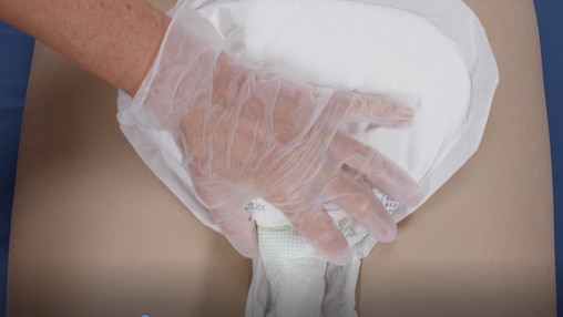 Fermo immagine del video in cui un caregiver aiuta il proprio caro in posizione supina a indossare gli assorbenti TENA.