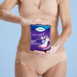 Woman holding a pack of TENA Discreet Maxi Night