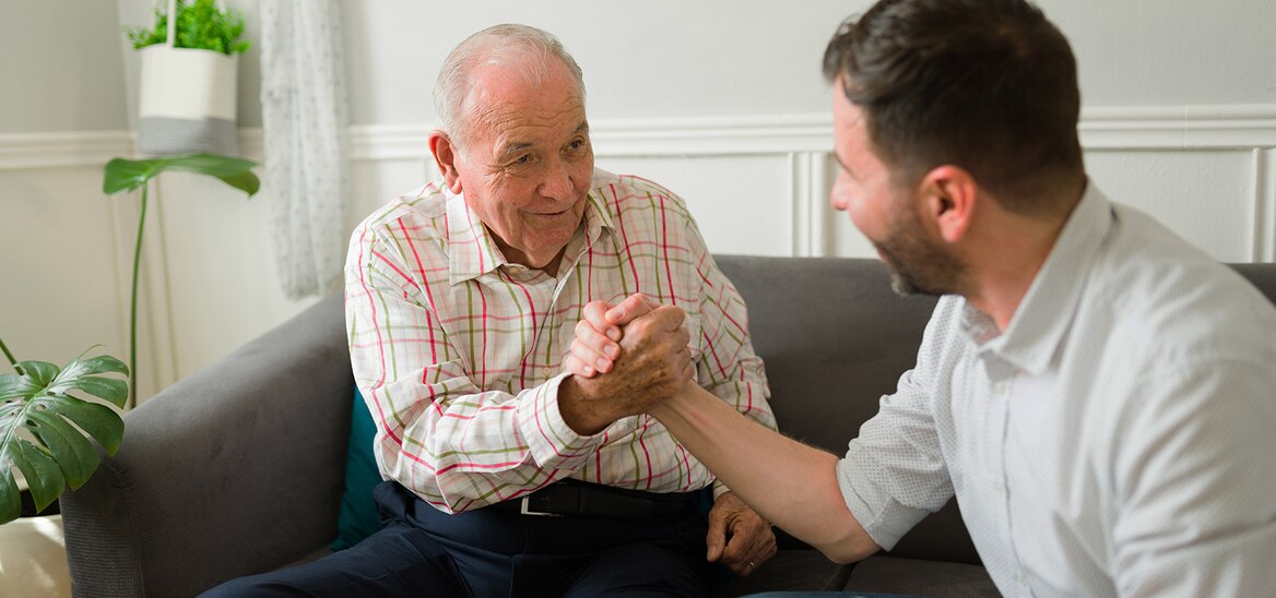 Caregiver che stringe la mano alla persona amata mentre sorride