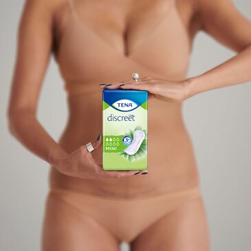 A woman holding a package of TENA Discreet Mini