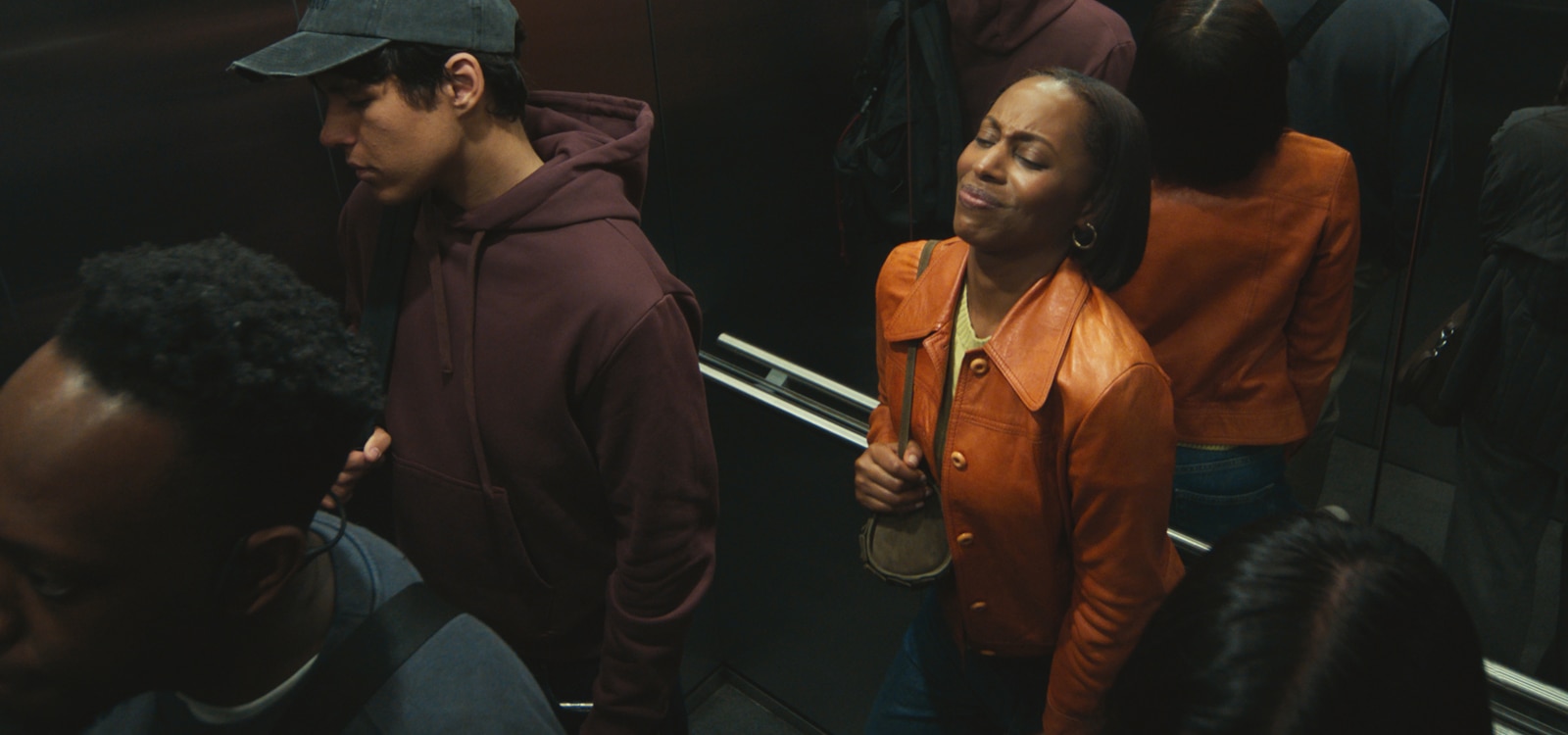 A woman in the back of the elevator suffering from itchiness