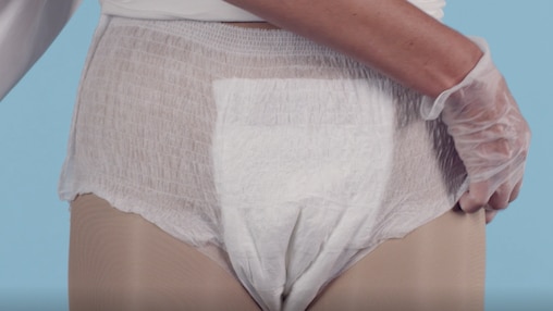 Sličica iz videoposnetka, ki prikazuje negovalca pri oblačenju hlačk TENA Pants bližnjemu.