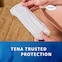 Een vrouw toont het TENA Discreet Ultra-verband, met de vertrouwde bescherming die u van TENA gewend bent