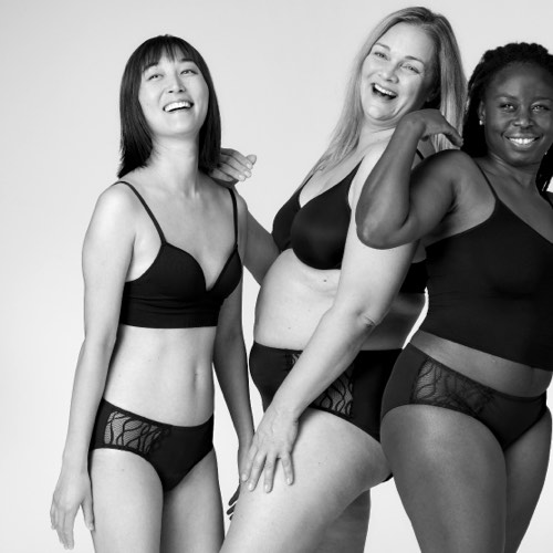 Three women standing next to each other laughing, all wearing TENA Silhouette Washable Absorbent Underwear.  