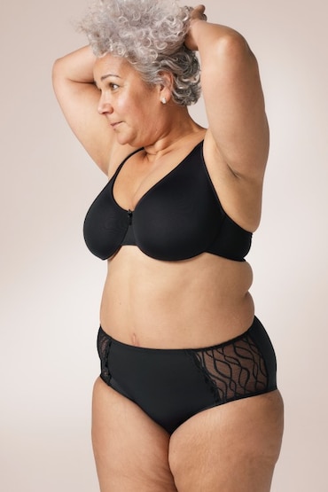 Weiße Frau, die einen schwarzen BH und die TENA Silhouette waschbare Unterwäsche als klassischen Slip trägt.