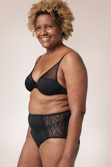 Afroamerikanische Frau, die einen schwarzen BH und die TENA Silhouette waschbare Unterwäsche als klassischen Slip trägt. Afroamerikanische Frau, die einen schwarzen BH und die TENA Silhouette waschbare Unterwäsche als klassischen Slip trägt.
