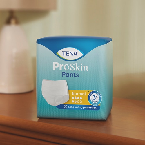 En förpackning med TENA ProSkin inkontinensskydd är utplacerade på en träyta. 