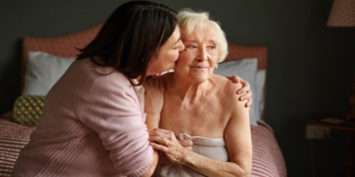 A caregiver kisses her relative on the cheek