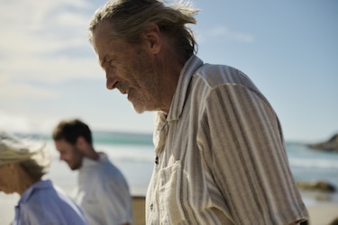 A close-up of a man walking on a beach with two friends