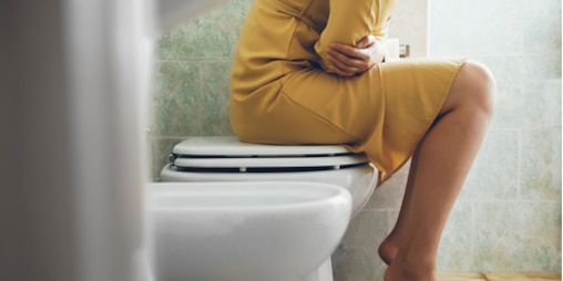Mujer sentada en un baño con dolor