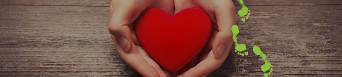 Cupped hands hold a red heart shape.
