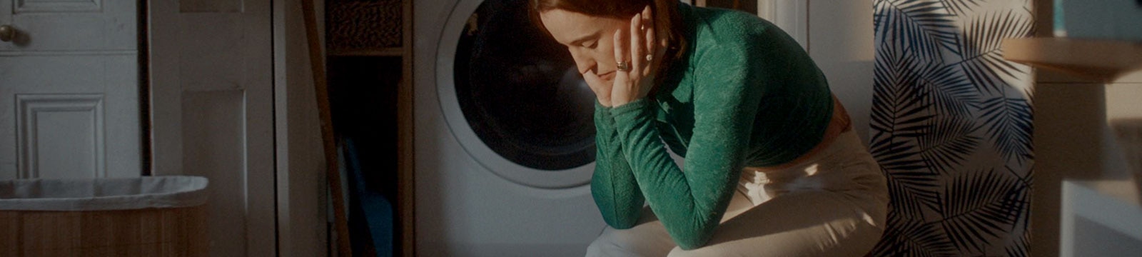 An exhausted woman sits alone in a laundry room