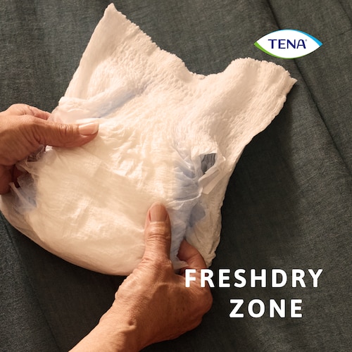 TENA Pants Protect+ werden in den Händen gehalten; Schwerpunkt auf die FreshDry Zone