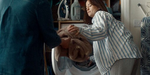 Une femme retire la lessive de la machine et la remet à sa mère.