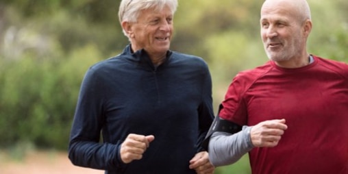 Two men in middle age are jogging together outdoors.