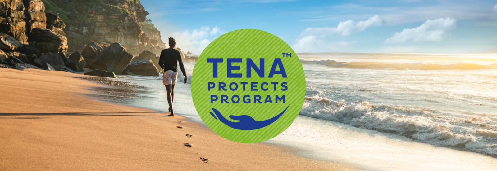 Logo programu TENA Protects přes fotografii muže kráčejícího po slunné pláži směrem ke vzdáleným útesům 