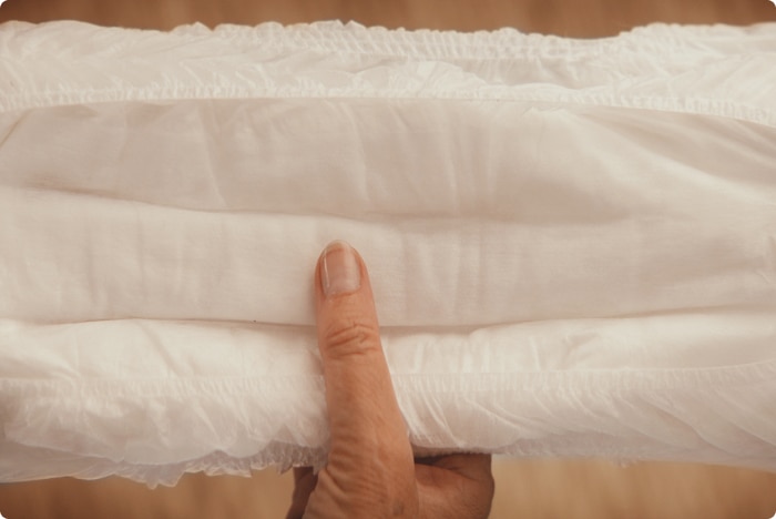 Image en gros plan de la main d'un soignant qui sent la surface sèche et absorbante d'un produit TENA.