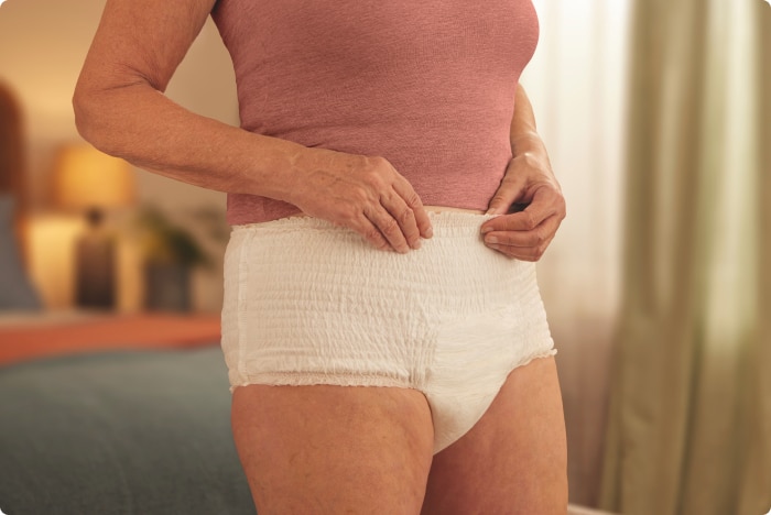 Image d'une femme à la maison portant un produit absorbant TENA Pants.