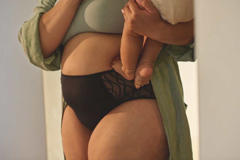 Woman in TENA underwear holding a baby