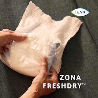 A segurar o produto TENA Pants protect+ nas mãos demonstrando a zona FreshDry