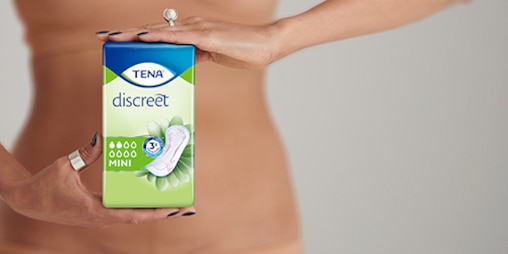 Women in underwear holding a TENA Discreet Mini pack