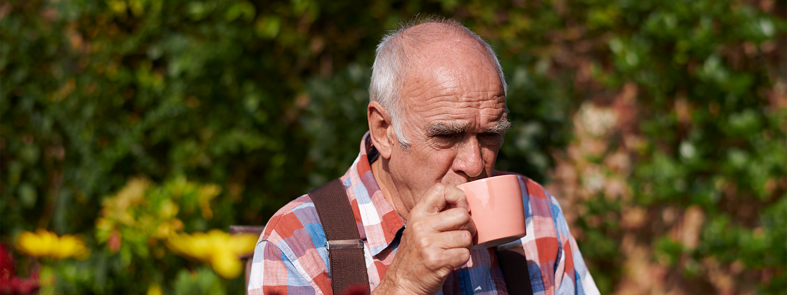 An elderly man, whose incontinence is now under control, enjoys drinking coffee.