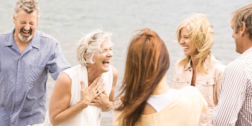Vier Freundinnen im reiferen Alter sind am Strand und lachen