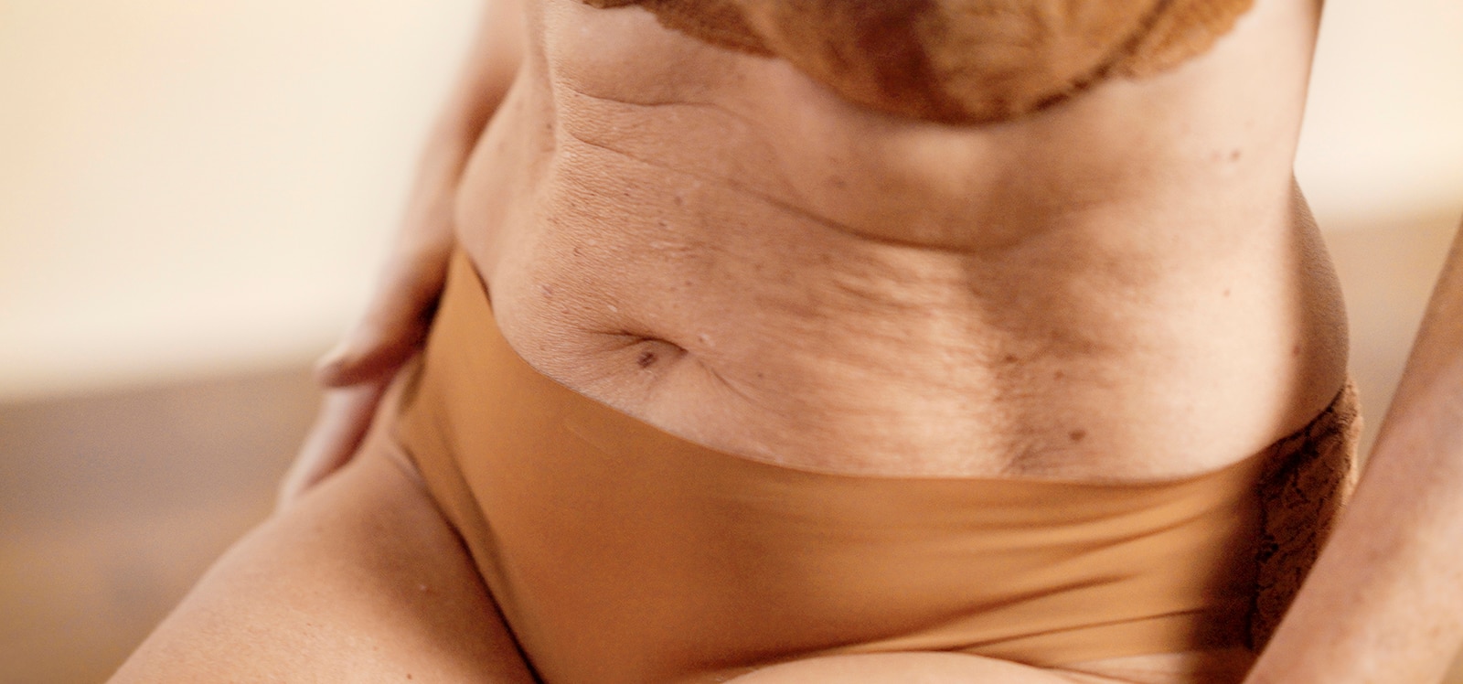 Nærbillede af maven på en ældre kvinde iført undertøj