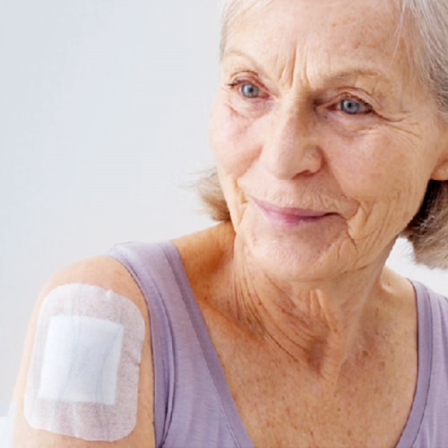 An elderly woman with a plaster on her shoulder.