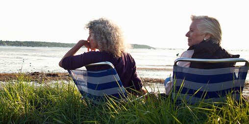 Twee oudere vrouwen die van het uitzicht genieten op het strand