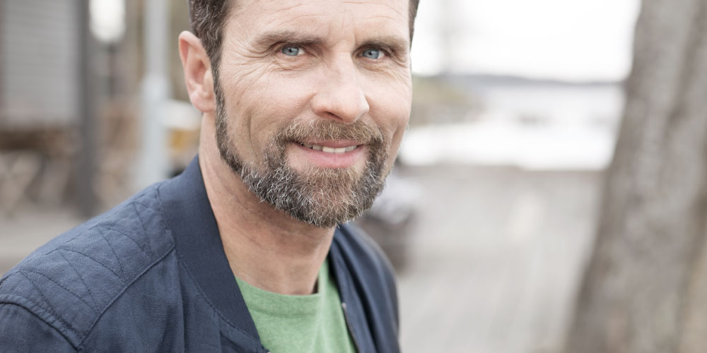 Brodaty mężczyzna w średnim wieku, uśmiechający się do aparatu