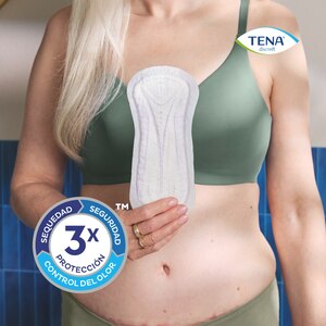 Mujer sosteniendo una compresa TENA Discreet Ultra delante de ella, con la afirmación de la triple protección de TENA de sequedad, seguridad y control del olor