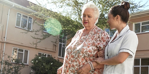 屋外を散歩する看護師と高齢女性