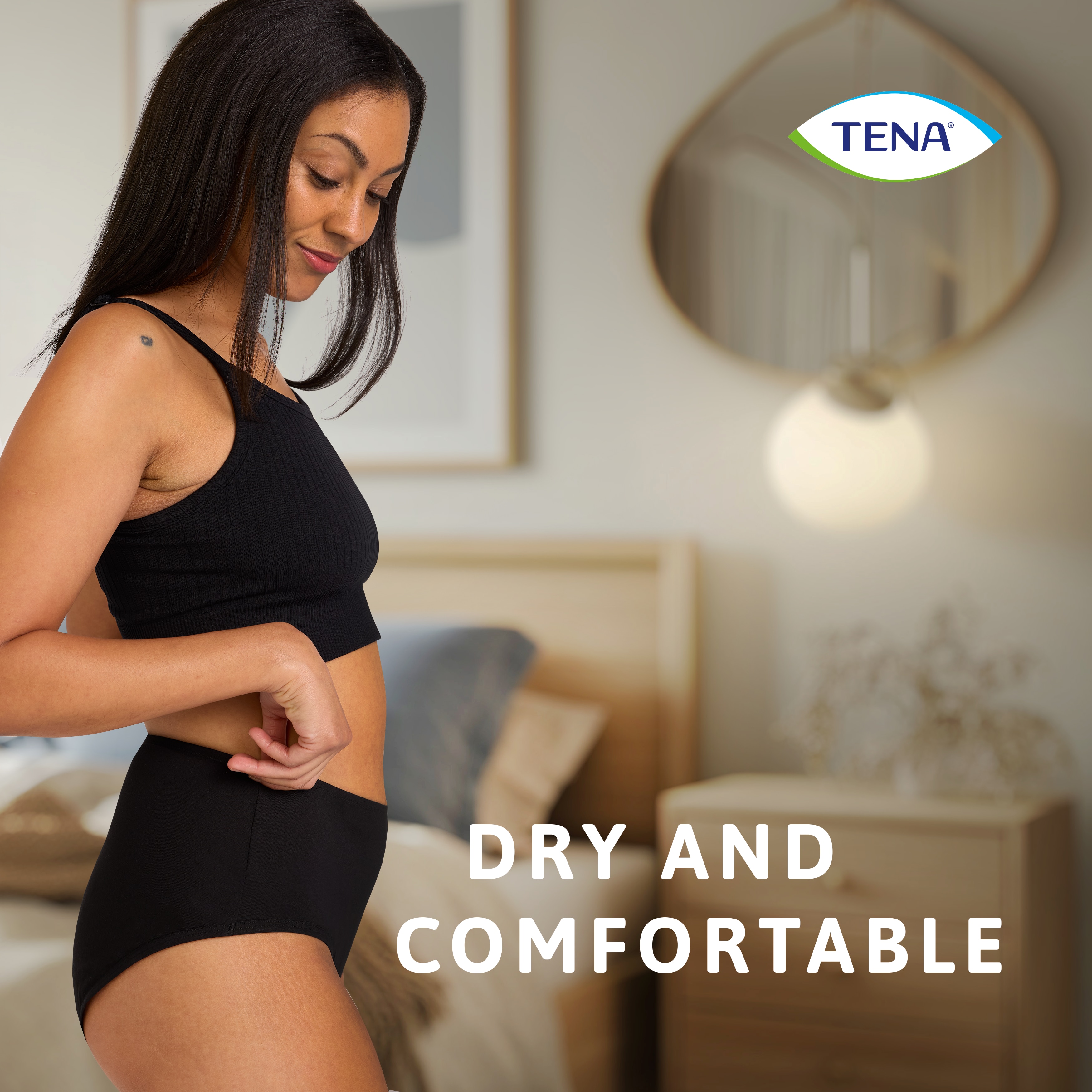 Mulher a utilizar a roupa interior lavável TENA Soft Cotton no quarto com a legenda “Seca e confortável”