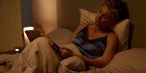 Donna a letto che legge un libro sui caregiver