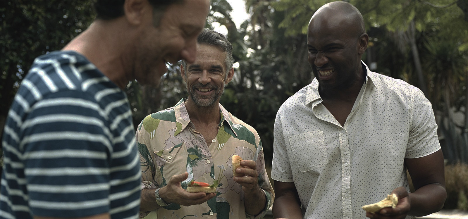 Three men at a barbeque, laughing 