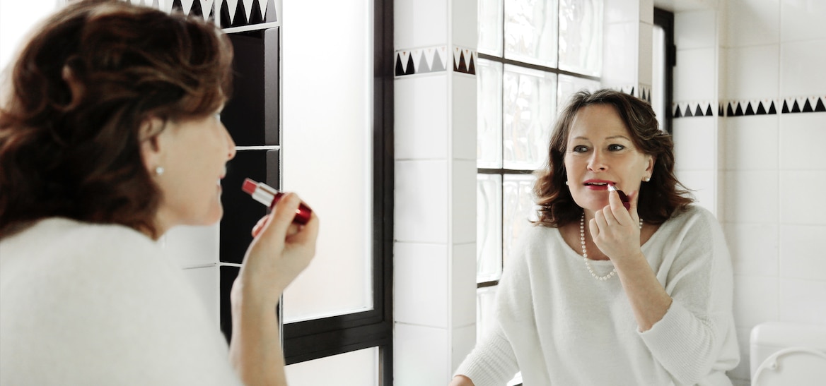 Mujer pintandose los labios frente a un espejo