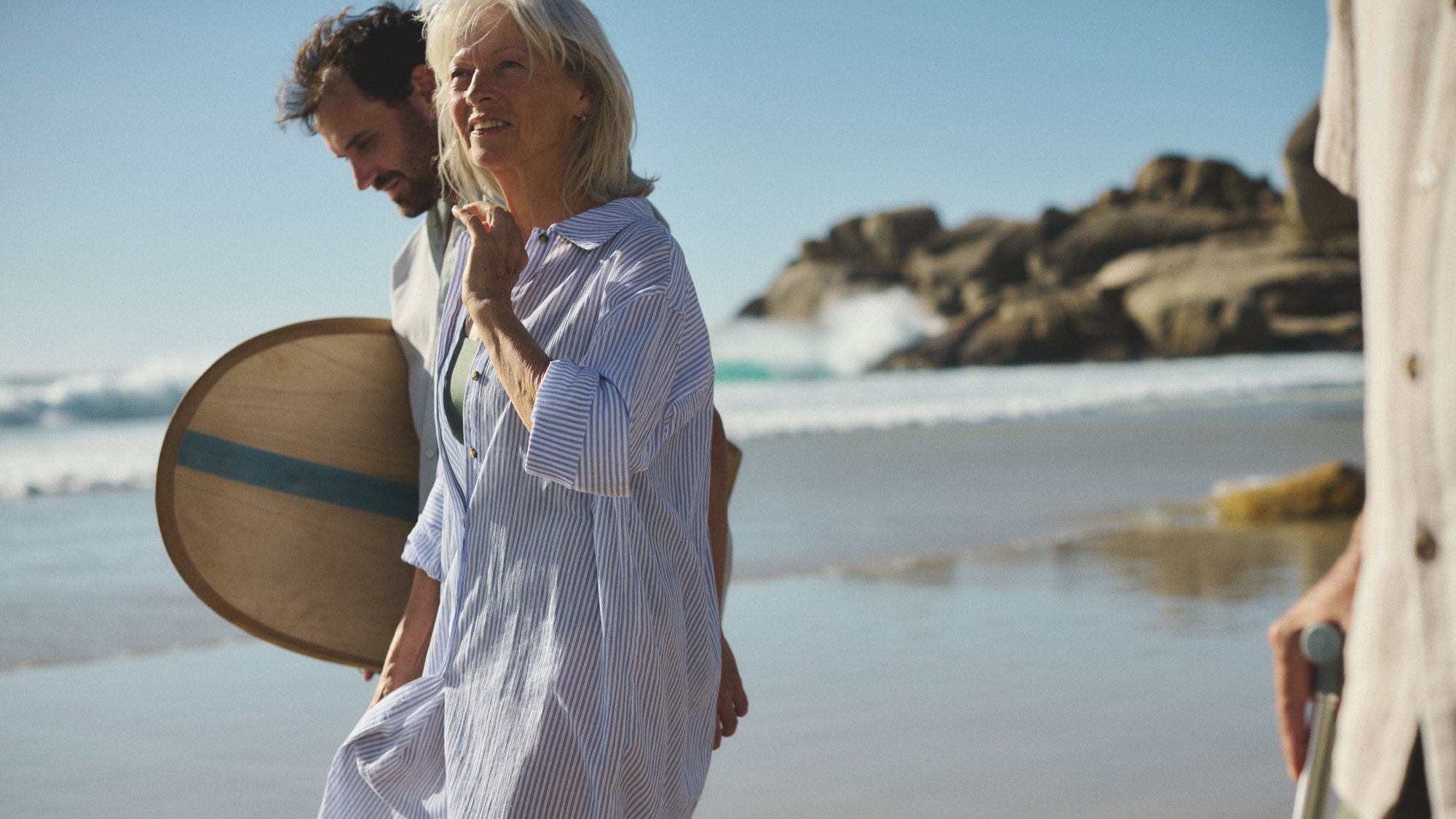 A woman and a man walking on a beach smiling.