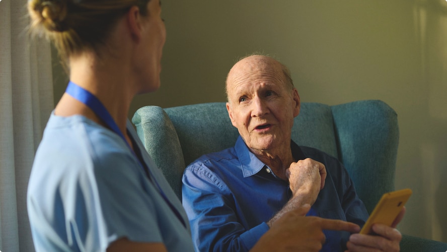 A nursing home resident is talking to a professional caregiver