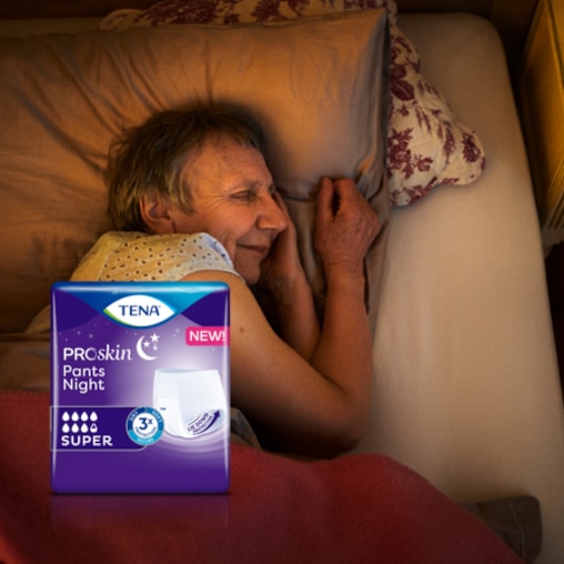 Eine ältere Frau schläft tief und fest in ihrem Bett. Im Vordergrund ist eine Packung TENA ProSkin Pants Night zu sehen.  