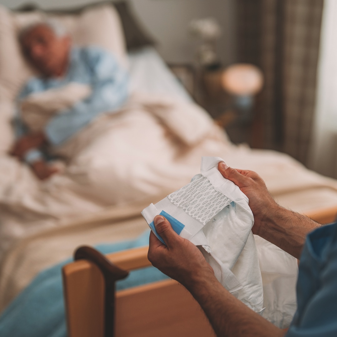 ベッドにいる入居者と、製品を持った看護師