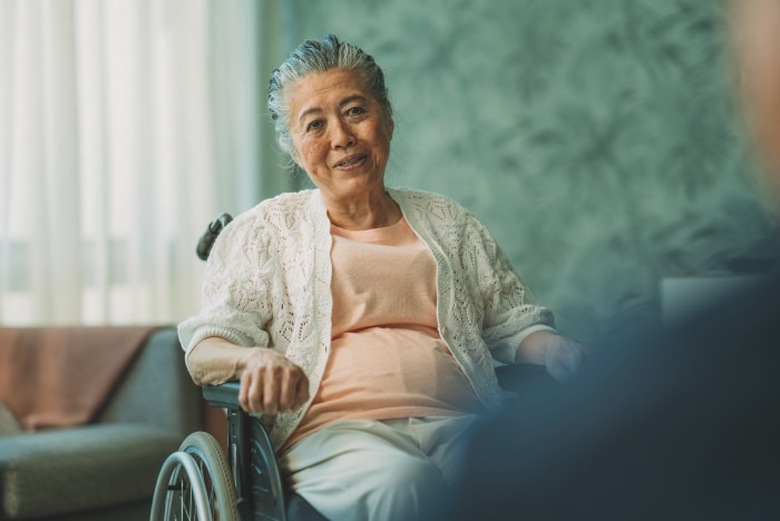 A contented nursing home resident sits in a wheelchair smiling