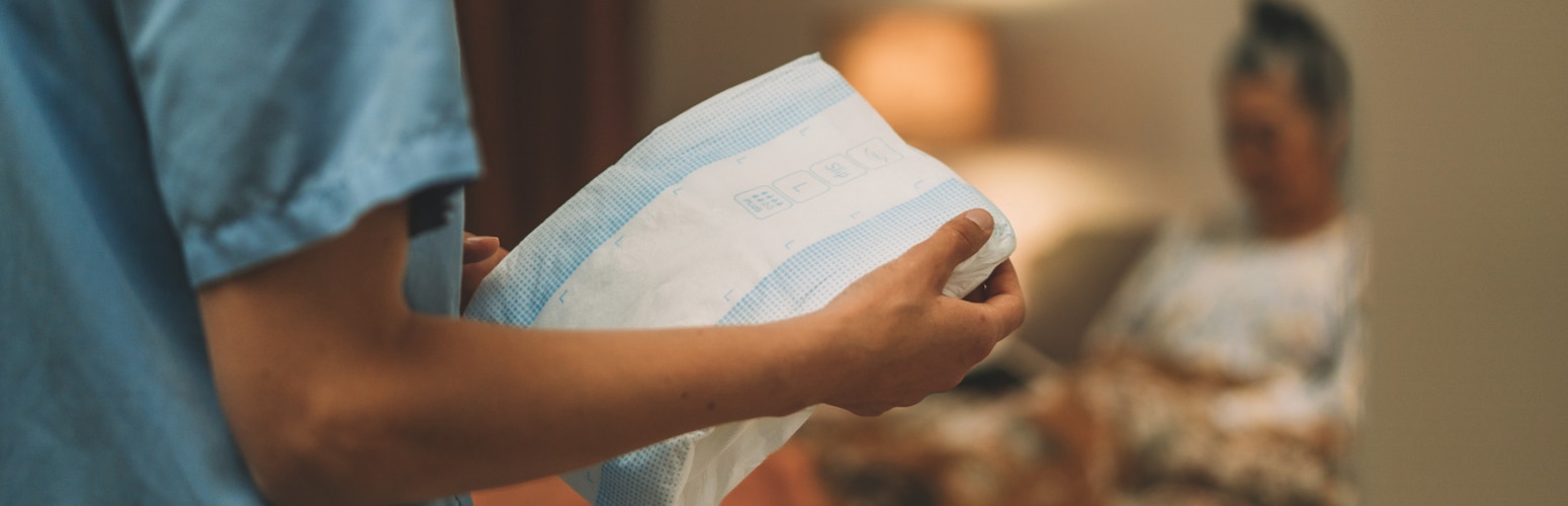 A professional caregiver holds improved TENA ProSkin Slip in a care facility