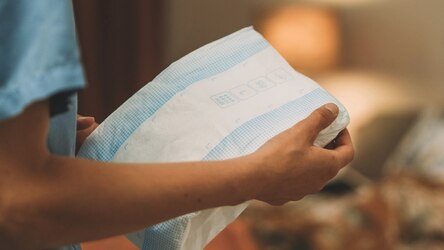 A professional caregiver holds improved TENA ProSkin Slip in a care facility