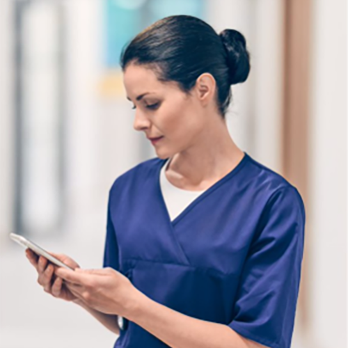 Sjuksköterska tittar på sin telefon.