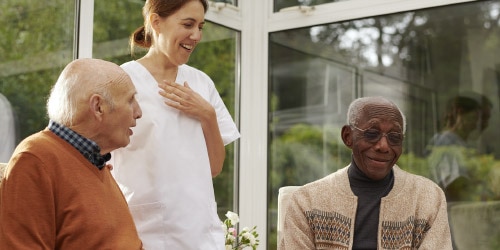 Care home residents talking outside with a nurse standing beside them