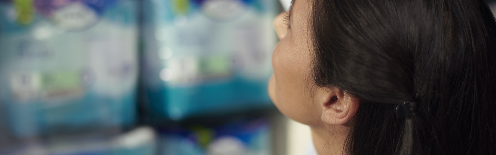 Farmasøyt ser på en hylle med TENA-produkter