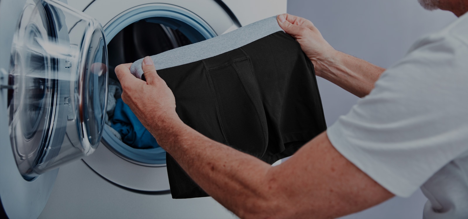 Man putting his TENA Washable Protective boxers in the washing machine