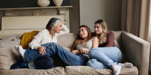  A mother in her fifties and her two teenaged daughters relax on the sofa.
