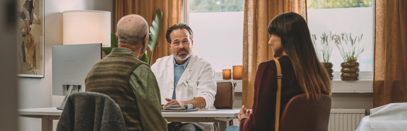 A doctor talks to a family carer and their loved one in the doctor’s office